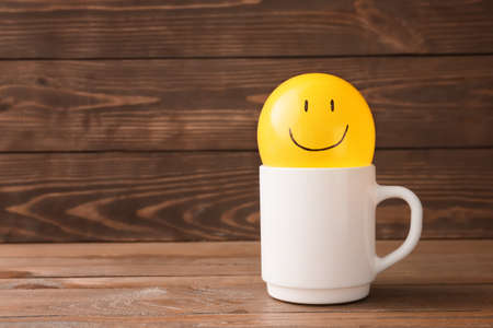 Air balloon with drawn happy face and cup on wooden backgroundの写真素材