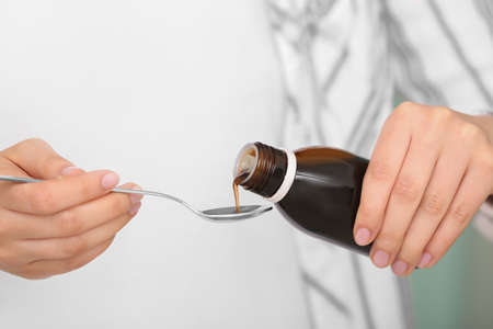 Woman pouring cough syrup from bottle, closeupの写真素材