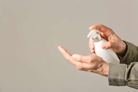 Man with sanitizer on gray background