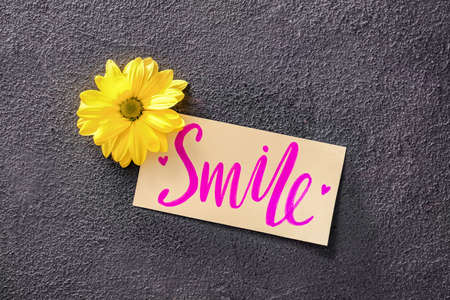Paper with word SMILE and flower on dark backgroundの写真素材