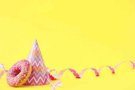 Party hat and donut on color backgroundの写真素材