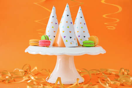 Party hats with decor and macarons on color backgroundの写真素材