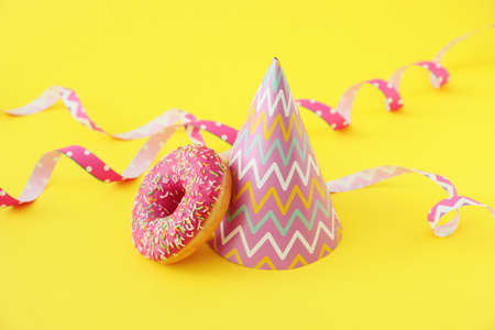 Party hat and donut on color backgroundの写真素材