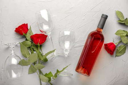 Bottle of wine, glasses and roses on light backgroundの写真素材