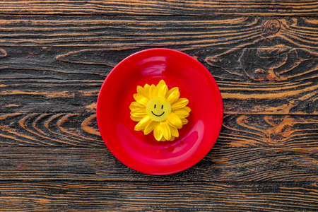 Plate with flower and paper smile on wooden backgroundの写真素材