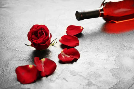 Bottle of wine and rose on gray backgroundの写真素材