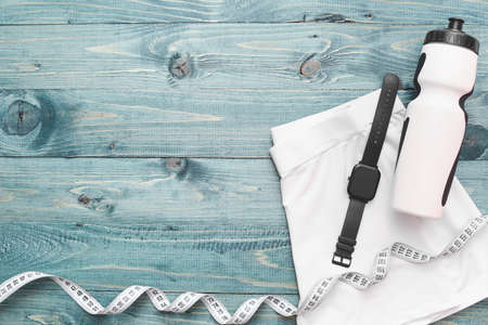 Sportswear, measuring tape, fitness tracker and bottle of water on color wooden backgroundの写真素材