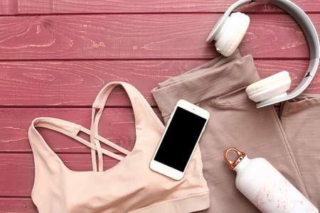 Sportswear, mobile phone, headphones and bottle of water on wooden backgroundの写真素材