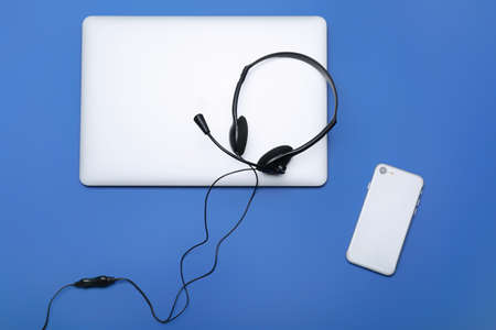 Laptop with headset and mobile phone on color backgroundの写真素材