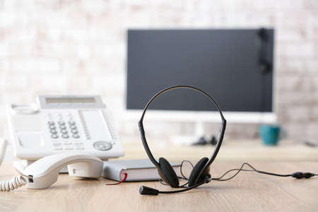 Headset and telephone on table of technical support agent in officeの写真素材