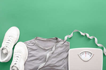 Sportswear, measuring tape and weight scales on color backgroundの写真素材