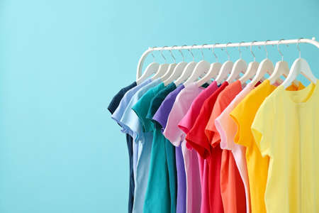 Rack with hanging clothes on color backgroundの写真素材