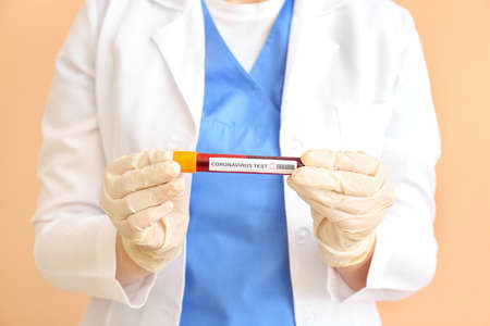 Doctor with blood sample on color background. Concept of Coronavirus epidemic
