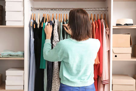 Woman choosing clothes from wardrobe at home