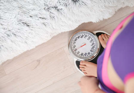 Young woman measuring her weight at home
