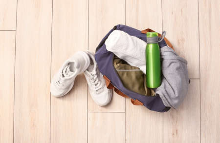 Bag with sportswear, equipment and shoes on wooden backgroundの写真素材