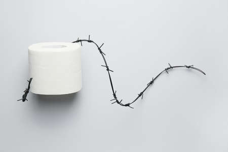 Toilet paper with barbed wire on light background. Hemorrhoids conceptの写真素材