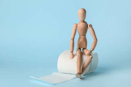 Toilet paper with wooden human figure on color backgroundの写真素材
