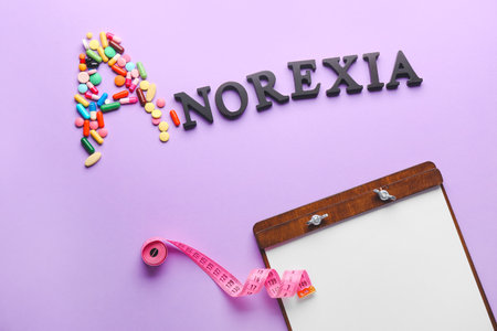 Word ANOREXIA, pills, clipboard and measuring tape on color backgroundの写真素材