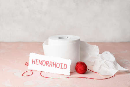 Toilet paper with red thread on color table. Hemorrhoids conceptの写真素材