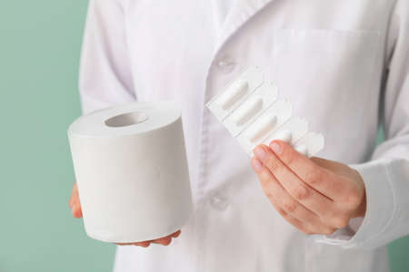 Doctor with toilet paper and hemorrhoidal suppositories, closeup