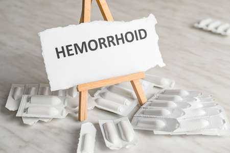Hemorrhoidal suppositories and paper with word HEMORRHOID on light backgroundの写真素材