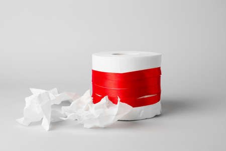 Toilet paper with red ribbon on light background. Hemorrhoids conceptの写真素材