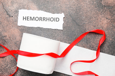 Toilet paper with red ribbon on gray background. Hemorrhoids conceptの写真素材