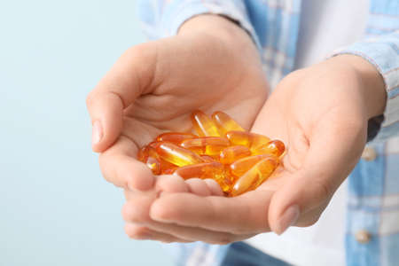 Woman with fish oil capsules, closeup