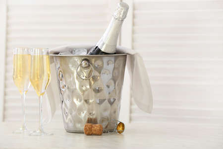 Bucket with bottle and glasses of champagne on tableの写真素材