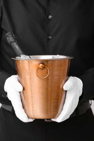 Waiter holding bottle of champagne in bucket, closeupの写真素材