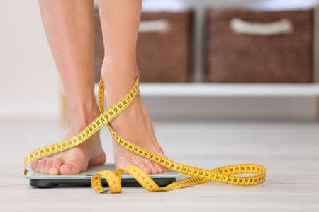 Young woman measuring her weight at homeの写真素材