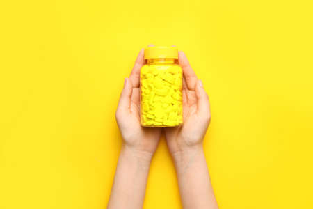 Female hands with pills in bottle on color backgroundの写真素材