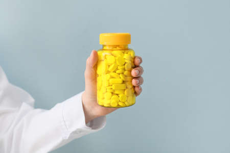 Female doctor with bottle of pills on color backgroundの写真素材