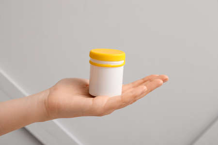 Female hand with bottle of pills on gray backgroundの写真素材