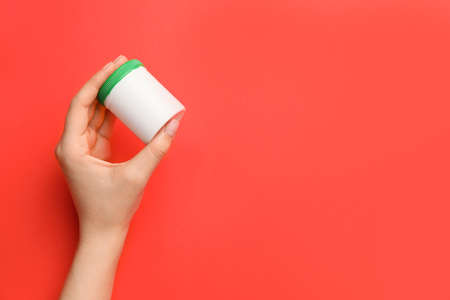 Female hand with bottle of pills on color background