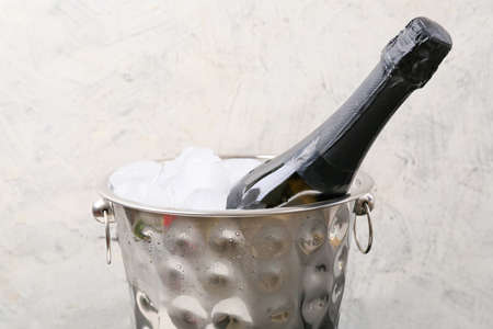 Bucket with ice and champagne on light backgroundの写真素材