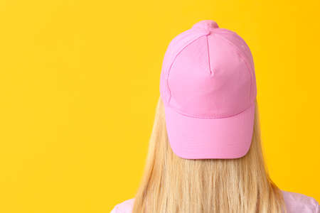 Beautiful young woman in stylish cap on color backgroundの写真素材