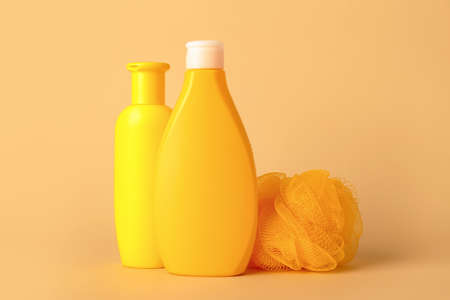Shower gels and loofah on color background