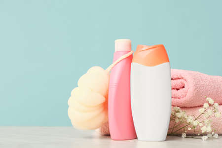 Shower gels, towels and loofah on color background