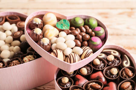 Heart-shaped boxes with delicious candies on wooden background