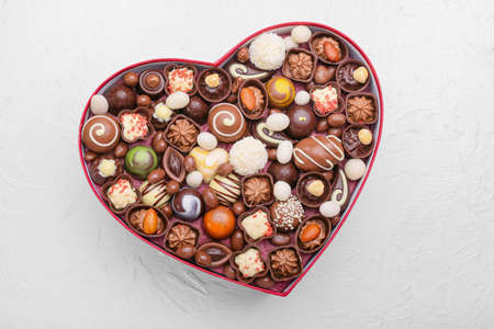 Heart-shaped box with delicious candies on white backgroundの写真素材
