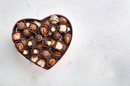 Heart-shaped box with delicious candies on light backgroundの写真素材