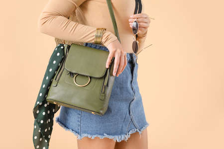 Beautiful young African-American woman with stylish bag on color backgroundの写真素材