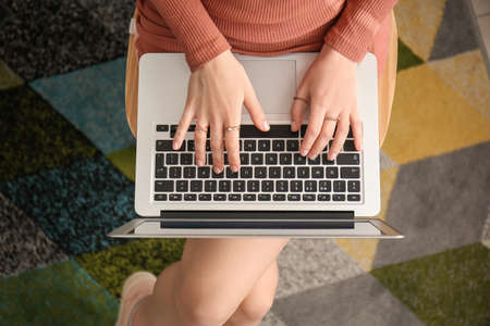 Young woman with laptop working at home, top view
