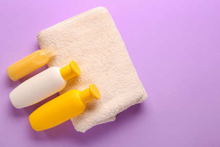 Different shower gels and towel on color background