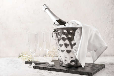 Bucket with ice and champagne on light backgroundの写真素材
