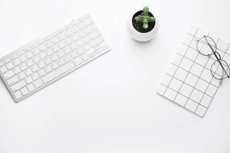 Computer keyboard with notebook and eyeglasses on white backgroundの写真素材