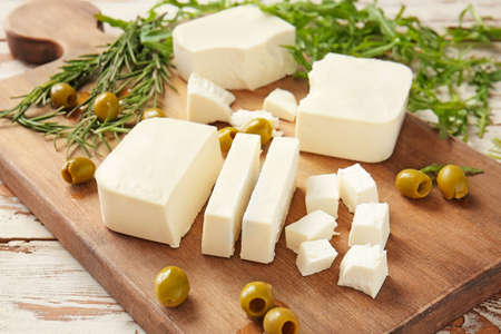 Tasty feta cheese with olives and herbs on board