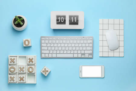 Computer keyboard with notebook, mobile phone, alarm clock and noughts-and-crosses game on color backgroundの写真素材
